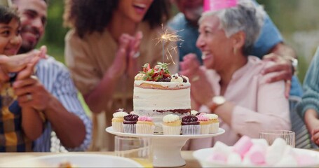 Birthday cake, sparkler and party with family for celebration, applause and surprise in garden of home. Dessert, senior woman and kids with cupcake, clapping hands and happiness for event in backyard