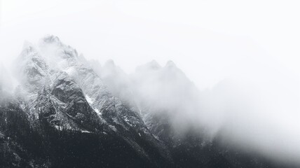 Dense fog envelops a secluded mountain range, creating a serene monochromatic scene