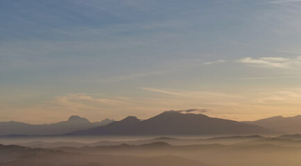 Fototapeta na wymiar Nebbia e sole avvolgono le montagne le coliine e le valli