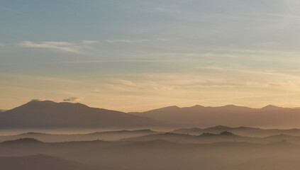 Fototapeta na wymiar Nebbia e sole avvolgono le montagne le coliine e le valli