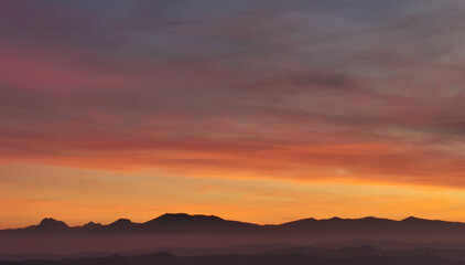 Il cielo rosso di nuvole sopra le montagne al tramonto