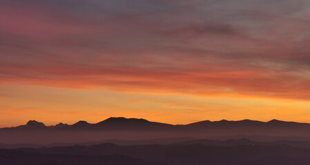 Il cielo rosso di nuvole sopra le montagne al tramonto