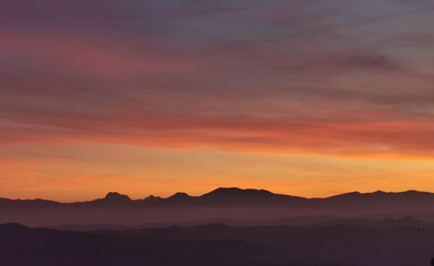 Obraz premium Il cielo rosso di nuvole sopra le montagne al tramonto