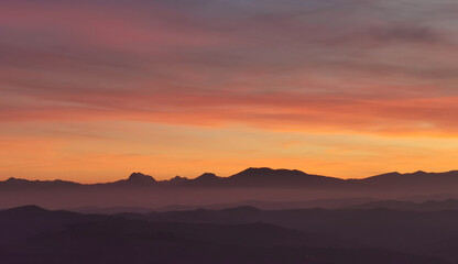 Il cielo rosso di nuvole sopra le montagne al tramonto