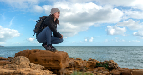 Sporty woman hiker on rocks by the sea