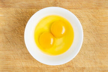 Raw eggs in bowl on the wooden table background. Studio photo. Shot from above. 
