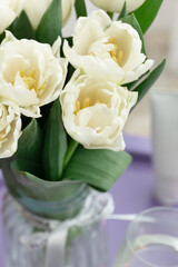 Obraz premium A bouquet of white tulips in a vase on a purple table decorated with red hearts. Valentine's Day, birthday, March 8. Top view.