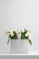 A bouquet of white tulips in a beautiful package on a white background. Birthday, Valentine's Day, March 8 and other holidays. Top view. Space for text.
