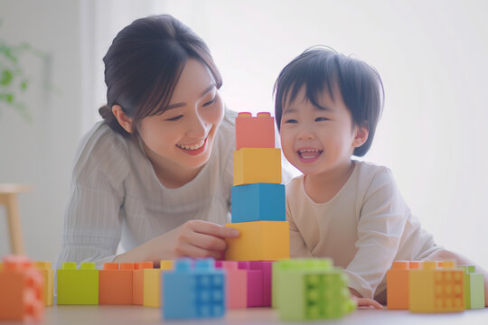 Young mother and her toddler enjoying playtime with colorful building blocks at home. Mother and Child Playing with Building Blocks...