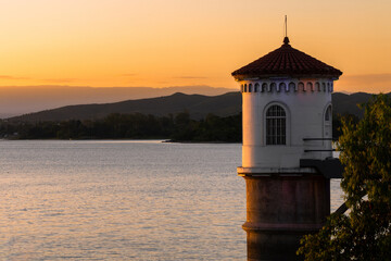 Fototapeta na wymiar Old dam tower on a beautiful summer sunset on the lake
