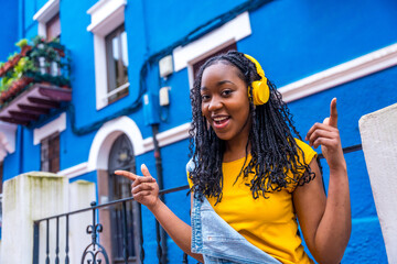 African woman singing while listening to music with headphones outdoors
