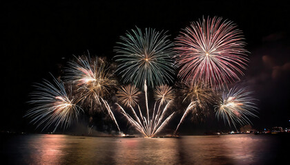 Colorful fireworks of various colors over night sky with reflection on water