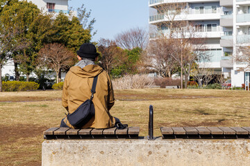 冬の公園のベンチに座る男性の後ろ姿