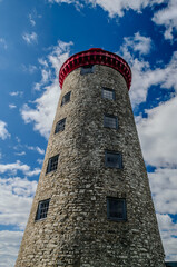 Historical windmill lighthouse tower reaching up to a clouded blue sky