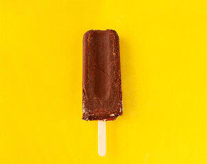 chocolate ice cream on a stick on yellow background