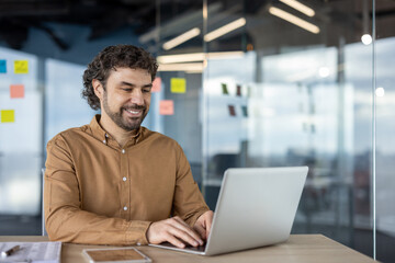 Mature experienced programmer inside office at workplace, businessman adult man typing on laptop keyboard, company worker in shirt satisfied with achievement results smiling.