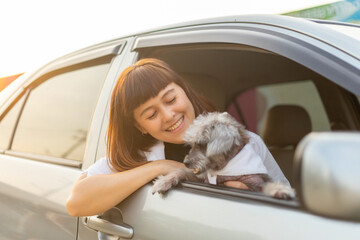 Young asian woman in casual outfit of cheerful with dog looking out of car window. Young female...