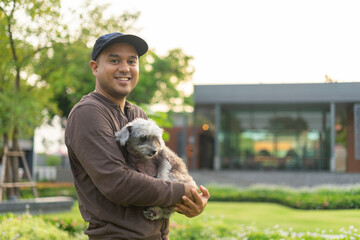 Yong asian man in casual outfit of cheerful with old dog at outdoors. Male playing with her little...