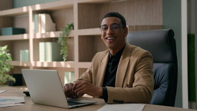 African American man ethnic 30s millennial businessman happy entrepreneur business employer office manager typing laptop computer looking at camera showing thumb up good recommend like approve gesture