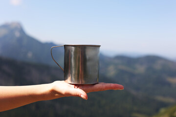 Mug in hand against the backdrop in the mountains