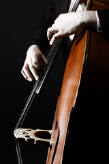 Double bass player. Hands playing contrabass strings music instrument