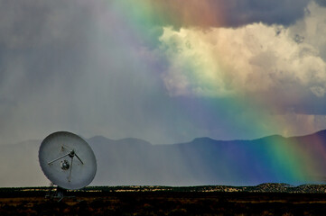Astronomical radio telescope with rainbow and rain squall on the Plains of San Agustin, New Mexico.