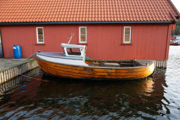 Fototapeta na wymiar Old wooden fishing boat by a bred boat house.