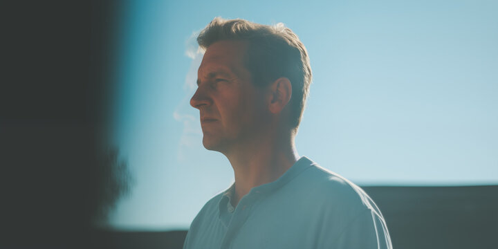 Mature man in a contemplative state, profile against the morning light, evoking a reflective mood - Powered by Adobe