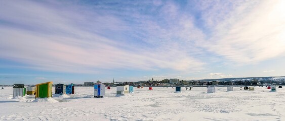 Scenic winter view of a beachfront featuring a collection of beach huts against a blanket of snow