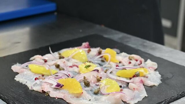 carpaccio di pesce crudo condito da un chef nella cucina di un ristorante di mare