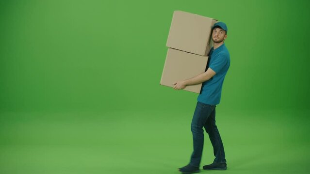 Green Screen Portrait of Handsome Delivery Person in Uniform Holds Cardboard Boxes and Smiles. Courier Working in Logistics Distribution Center, Delivering Online Orders. Great delivery service.