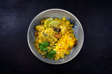 Traditional spicy Indian chicken Madras curry with chicken breast, cashew nuts and saffron rice served as top view in a Nordic design plate with copy space