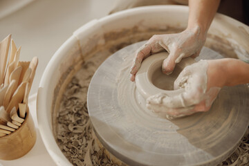Close up of hands of professional potter molding pot shape on pottery wheel. Ceramics art concept