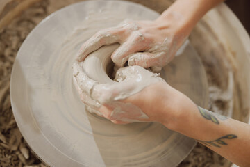 Fototapeta premium Close up of hands of professional potter molding pot shape on pottery wheel. Ceramics art concept