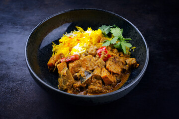 Traditional Indian vegetable curry with sweet potatoes, eggplant and saffron rice as close-up in a Nordic design plate