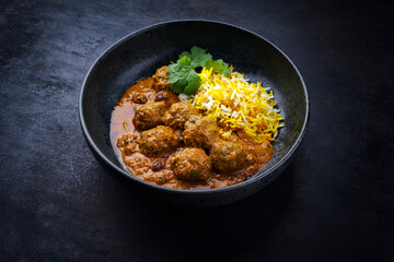 Traditional spicy Indian meat balls curry Rogan Josh with ground beef and saffron rice served as close-up in a Nordic design plate with copy space