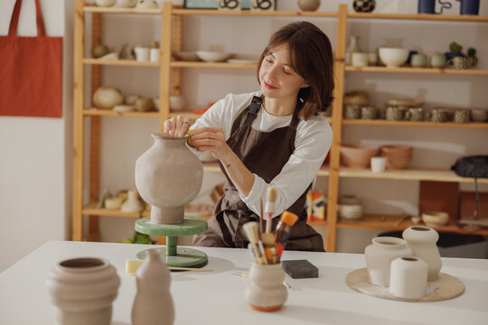 Professional female ceramist work with unfired clay vase in pottery studio. High quality photo