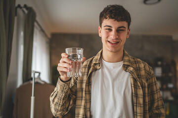 man young caucasian male teenager hold glass of water at home