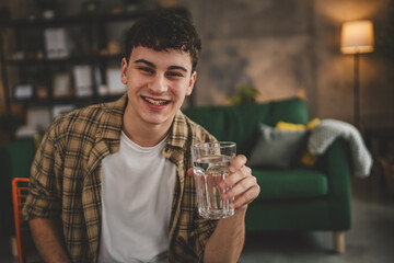 man young caucasian male teenager hold glass of water at home