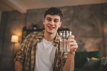 man young caucasian male teenager hold glass of water at home