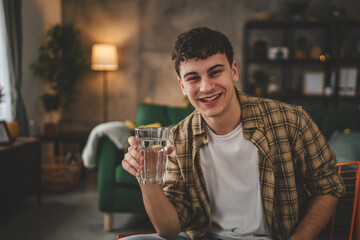man young caucasian male teenager hold glass of water at home