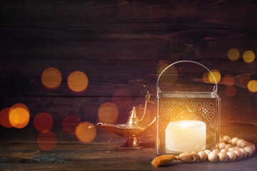 Muslim lantern with prayer beads and Aladdin lamp on dark wooden background