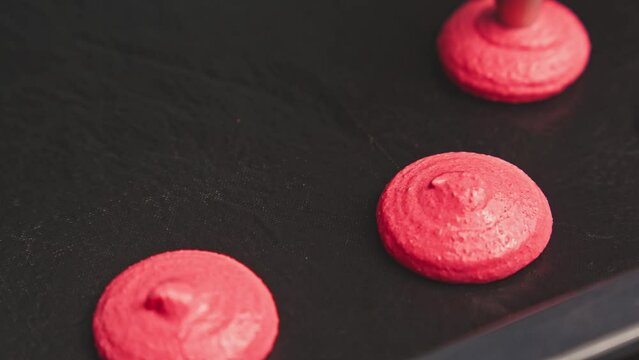Confectioner extruding macaroons from piping bag. Making pink macaroons. Baking concept. Making French dessert. Close-up in 4K, UHD