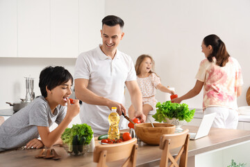 Naklejka premium Little boy with his father cooking in kitchen