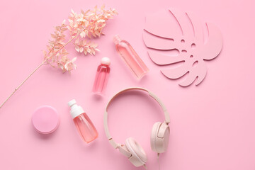 Obraz na płótnie Canvas Composition with modern headphones, bottles of cosmetic products and leaf on pink background