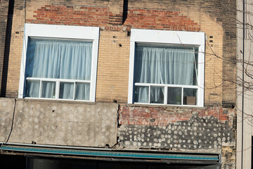 old commercial and residential unit facade with peculiar textures, new windows, and a tucked away retractable awning