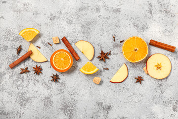 Orange with apple and different spices for preparing tasty mulled wine on grey background