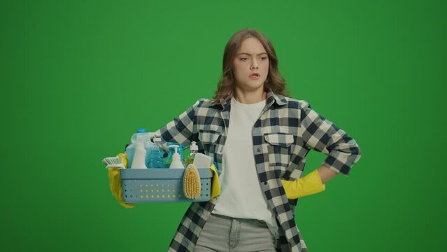 Green Screen. A Serious Young Woman in Yellow Protective Rubber Gloves Holding a Box With Cleaning Products and Inspects the Amount of Cleaning.Cleaning for Mental Clarity and Focus.