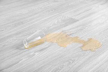 Wooden laminate floor with overturned glass of juice