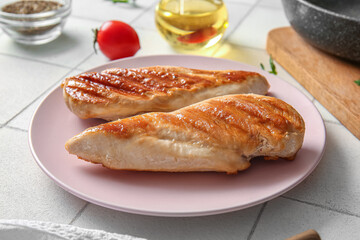 Plate with tasty grilled chicken breast on white tile background